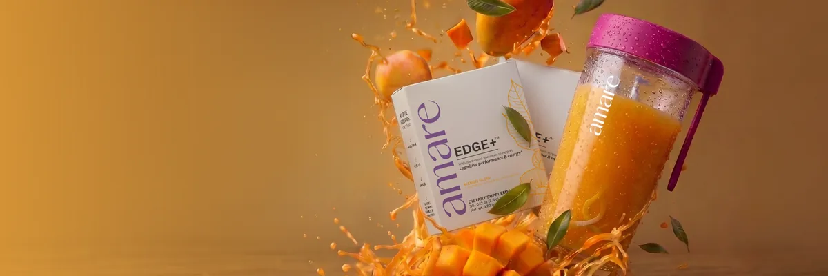 Two boxes of Amare EDGE+ Mango Glow beside a pink-lidded Amare Blender Cup, with splashing mango