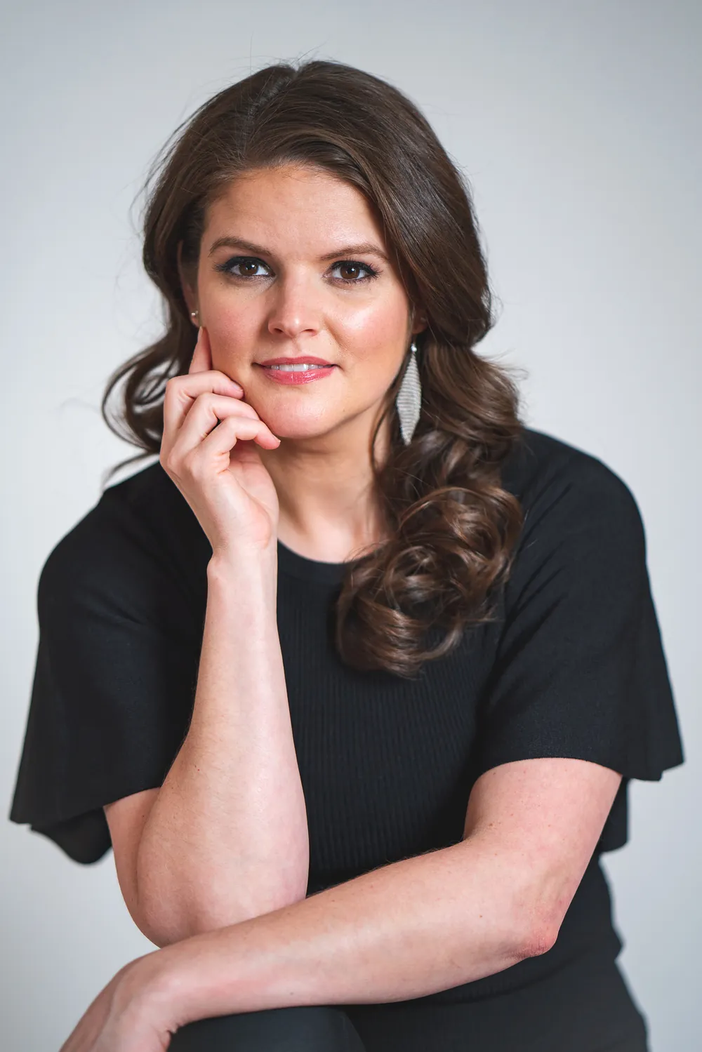 Lindsey Elmore, resting her chin on her hand, against a pale grey background