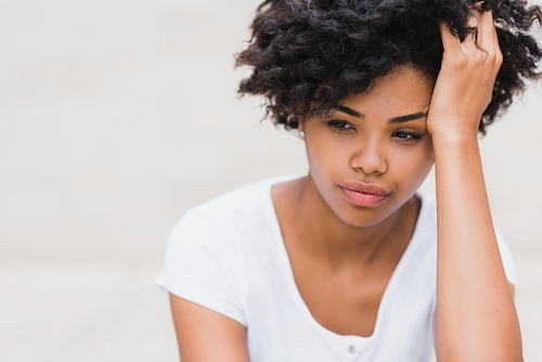 Beautiful Young Black Woman With Sad Pensive Reflective Look Against White Wall Background 